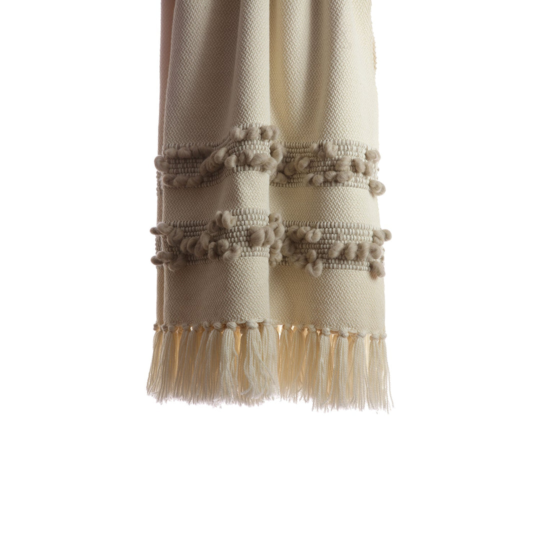 Close-up of the grey melange bobbled bands and knotted fringe on an ivory wool throw.