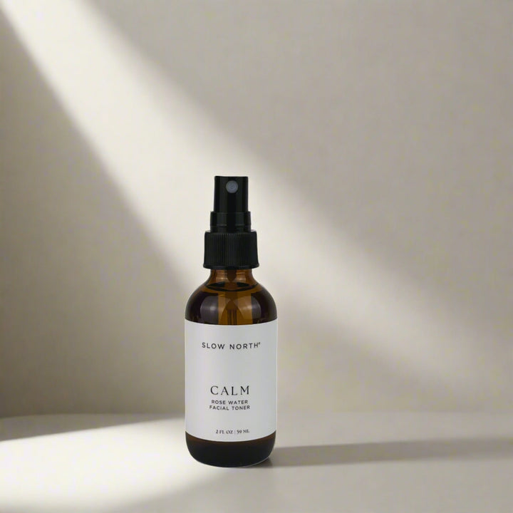 Calm Rose Water facial toner shown in a clear glass bottle with botanical ingredient detail.