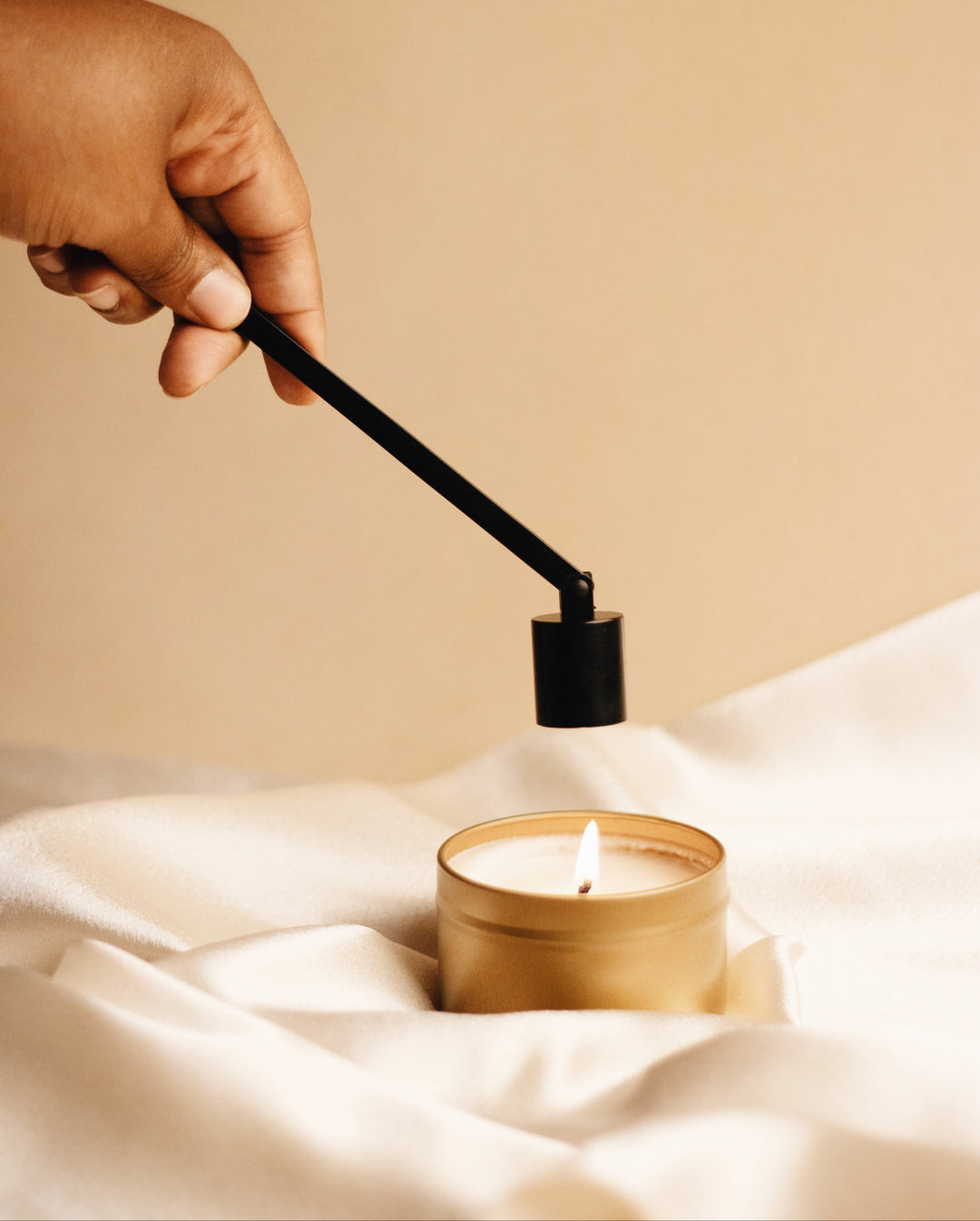 Candle care tools in black stainless steel arranged on a wooden surface.