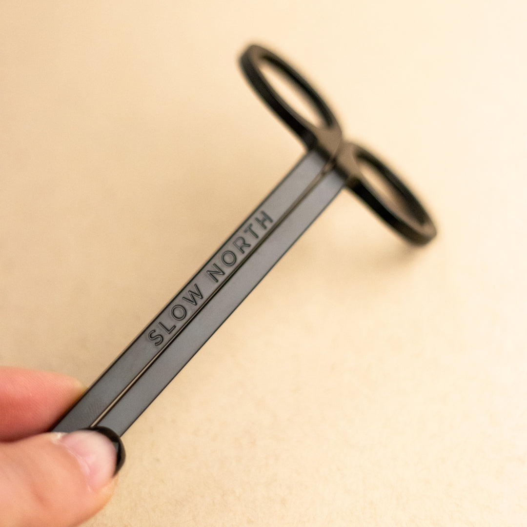 Black stainless steel candle care tool set on a white background.