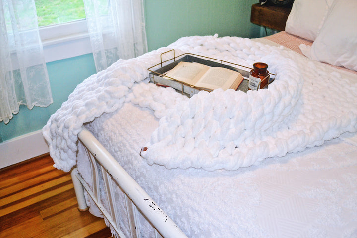 White chunky knit chenille throw blanket shown folded on a neutral background.