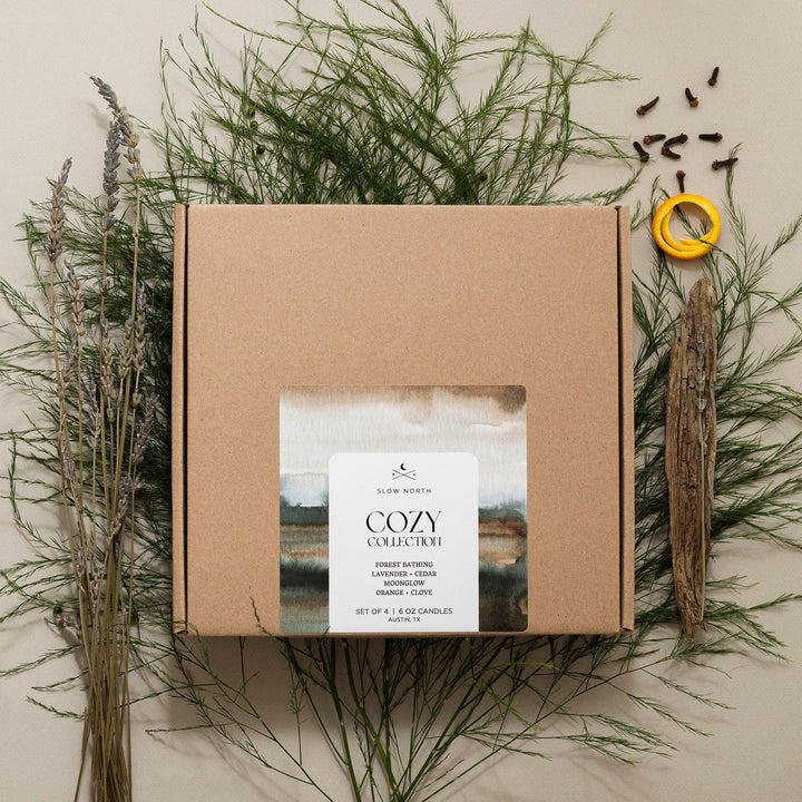 Four soy travel tin candles arranged in a kraft Cozy Collection gift box.