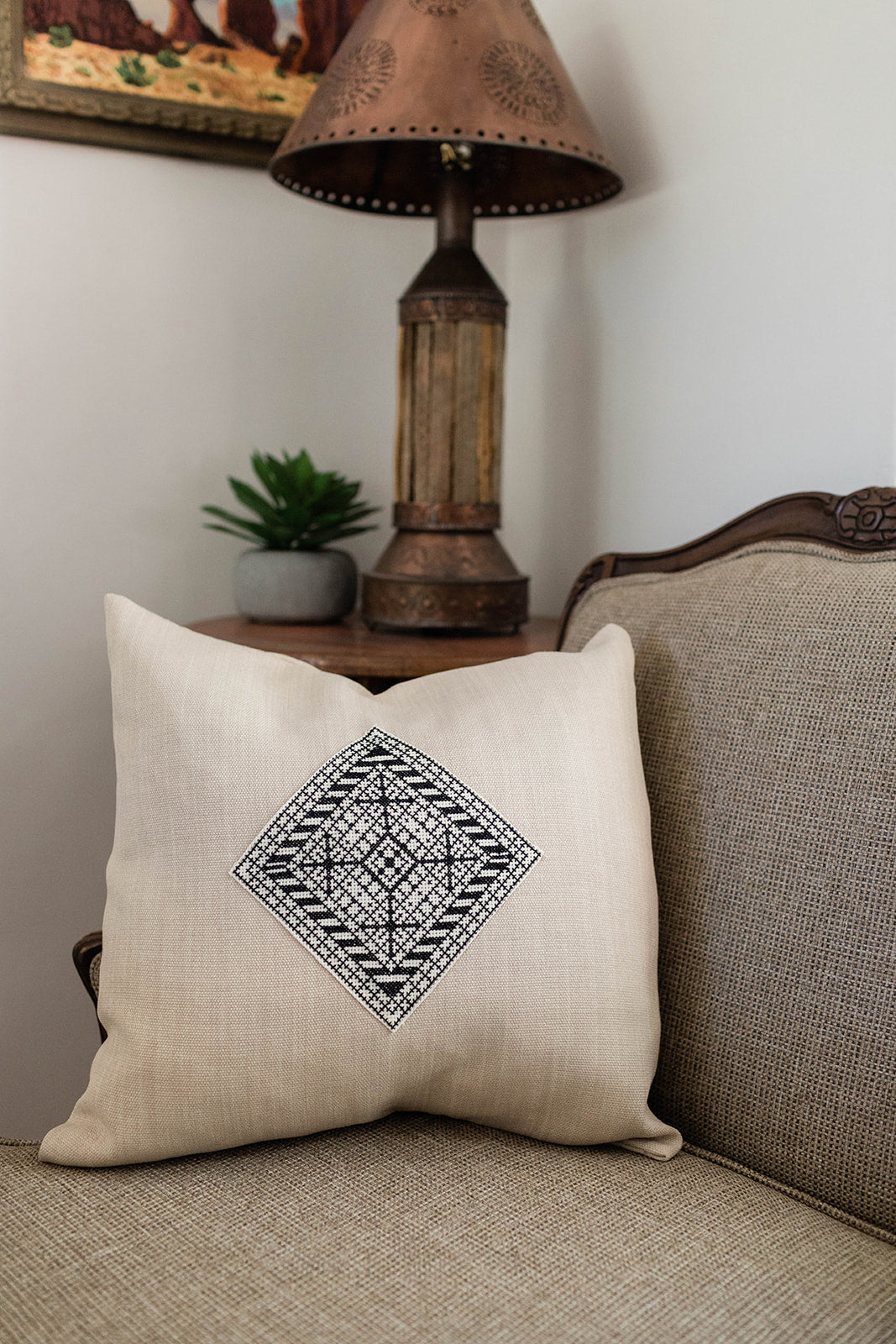 Hand-embroidered cushion cover, a bold black-and-ivory Diamond cross-stitch motif on natural cotton.