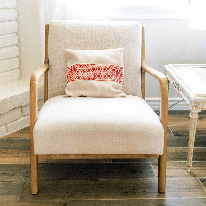 Hand-embroidered cushion cover with a red cross-stitch band on natural cotton.