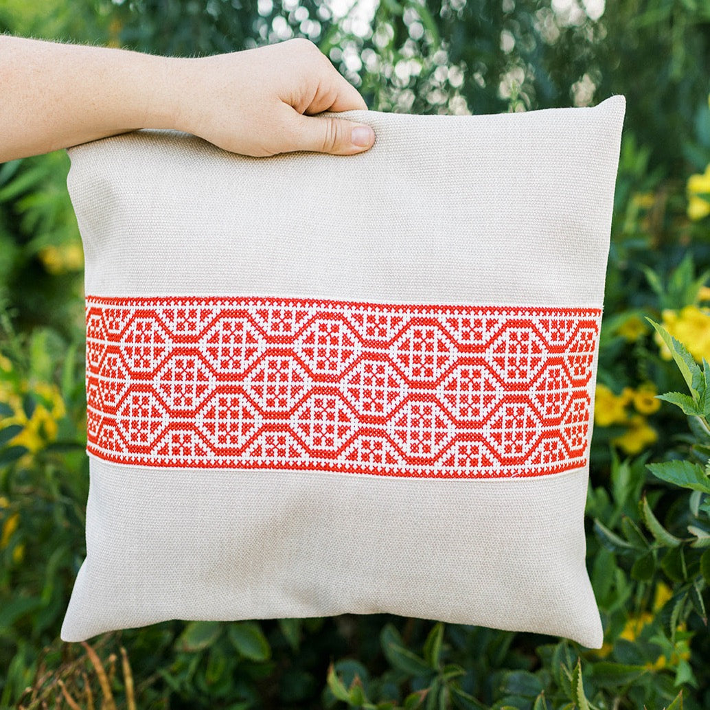 Natural oatmeal pillow cover with a bold red geometric tatreez band.