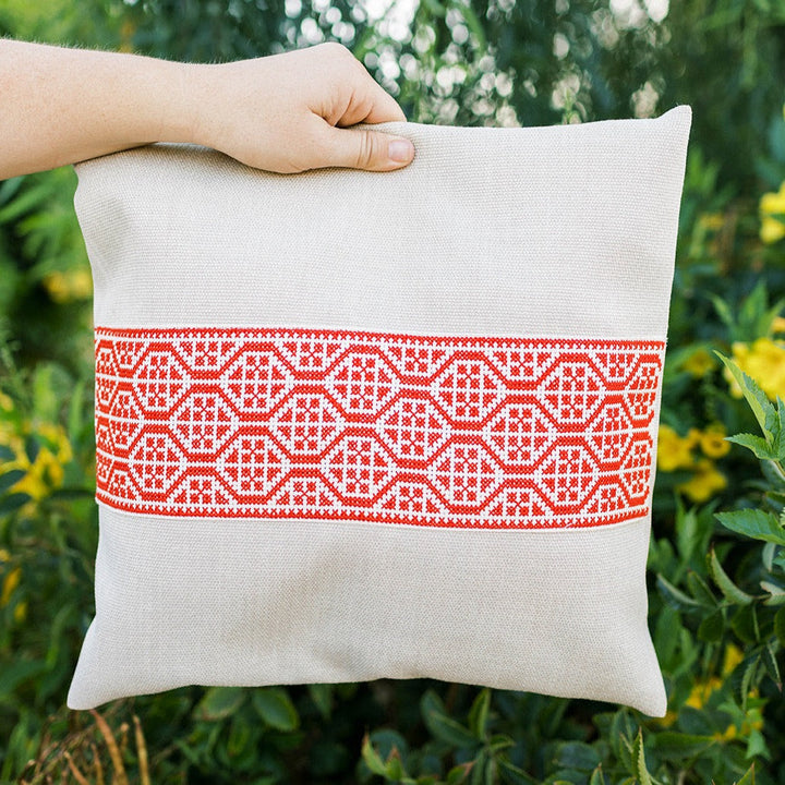 Natural oatmeal pillow cover with a bold red geometric tatreez band.