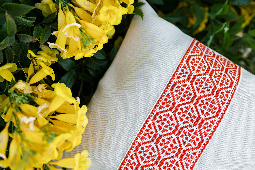 Close-up of the red geometric tatreez embroidery on a natural pillow cover.