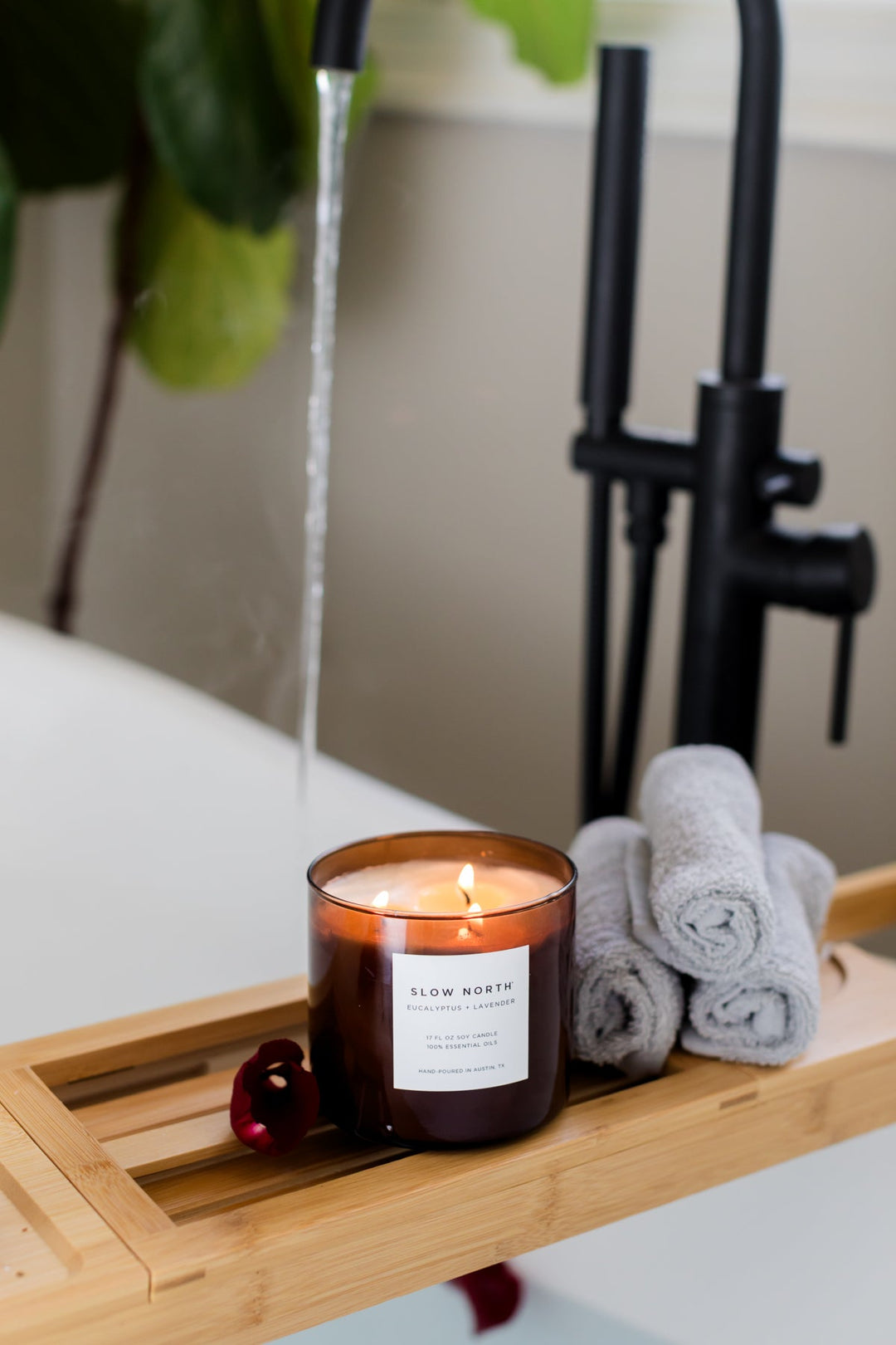 Eucalyptus Lavender three-wick candle with lit wicks in a clear glass jar.