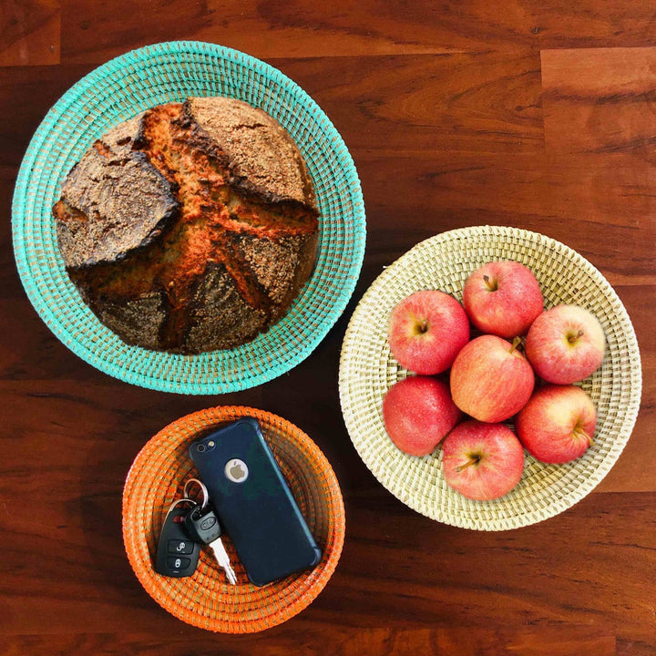 Colorful woven basket bowl set on a neutral surface.