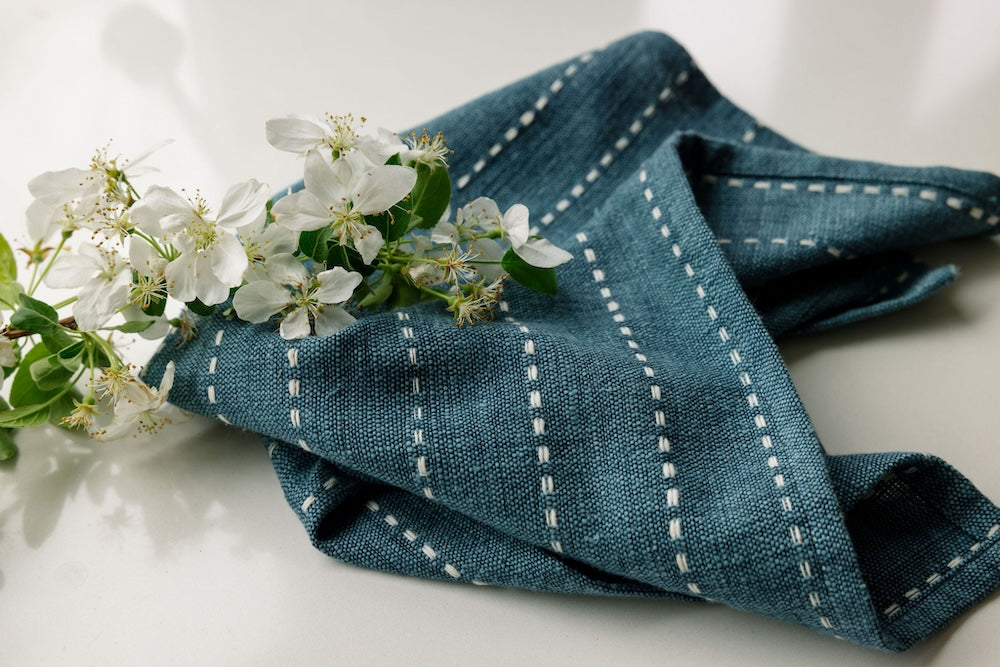 Steel blue cocktail napkin with a sprig of white flowers