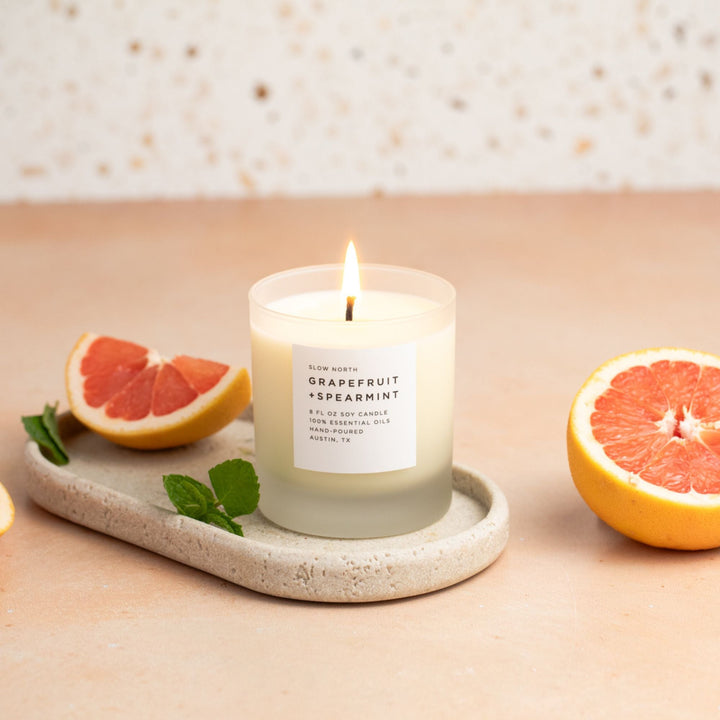 Grapefruit Spearmint candle in a sleek glass holder with lit wick.