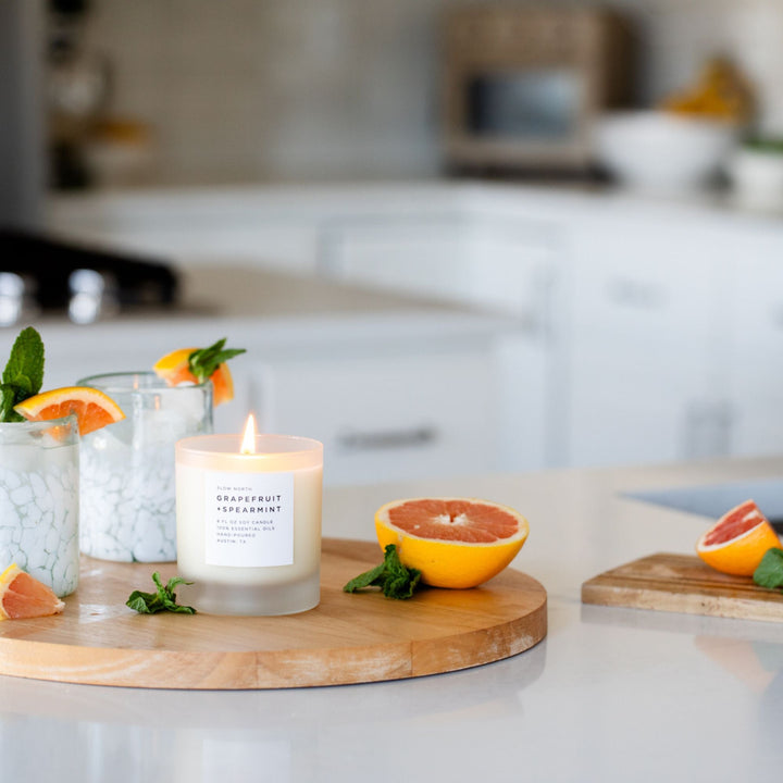 Grapefruit Spearmint candle with lit wick in a stylish glass jar.