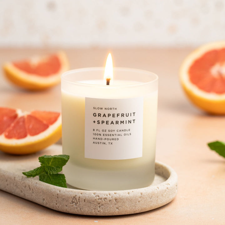 Citrus and mint signature candle with lit flame and clean scent profile.