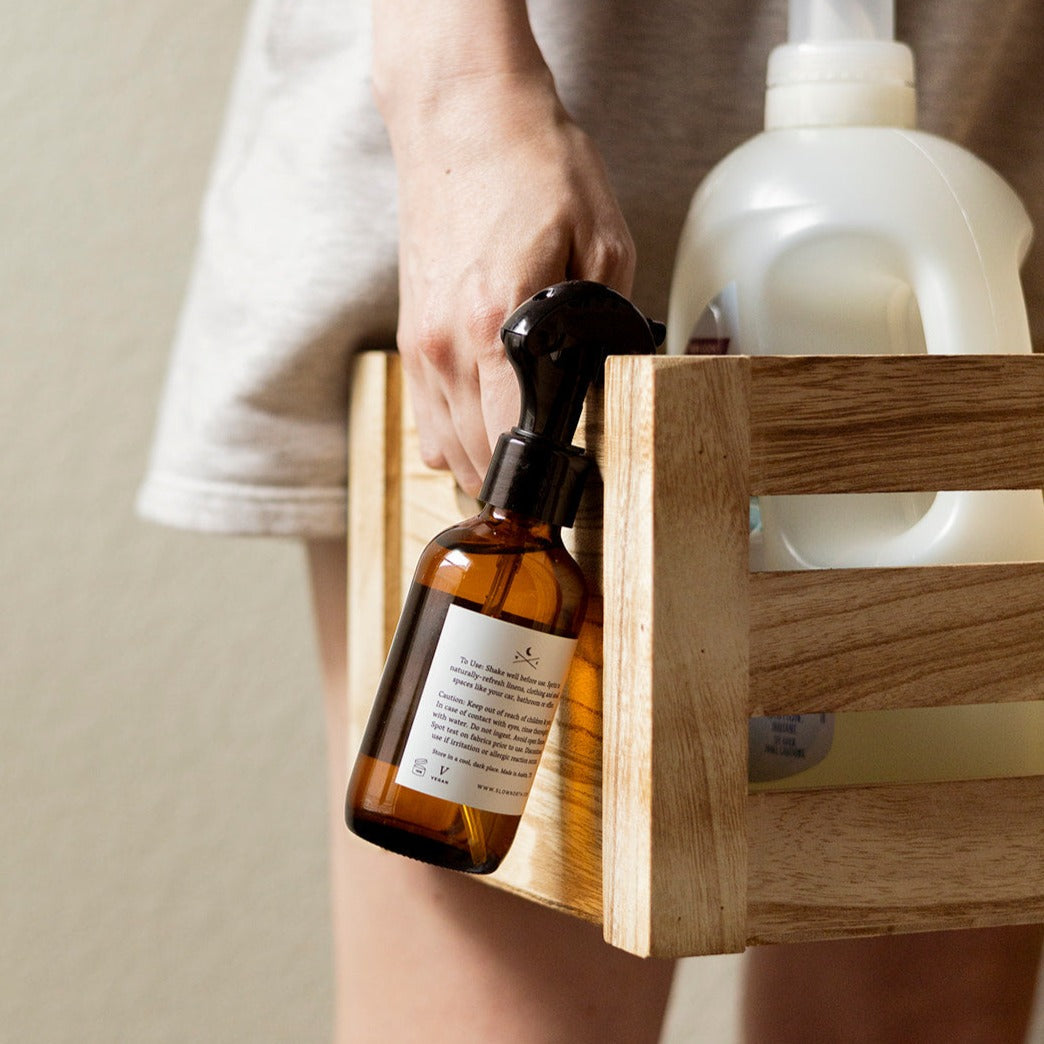 Linen spray bottle with sprigs of rosemary and lemon for natural fabric freshness.