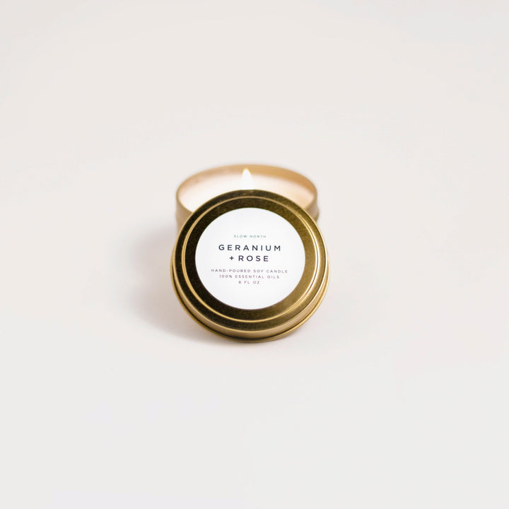 Geranium Rose travel tin candle with floral design and soft glow.