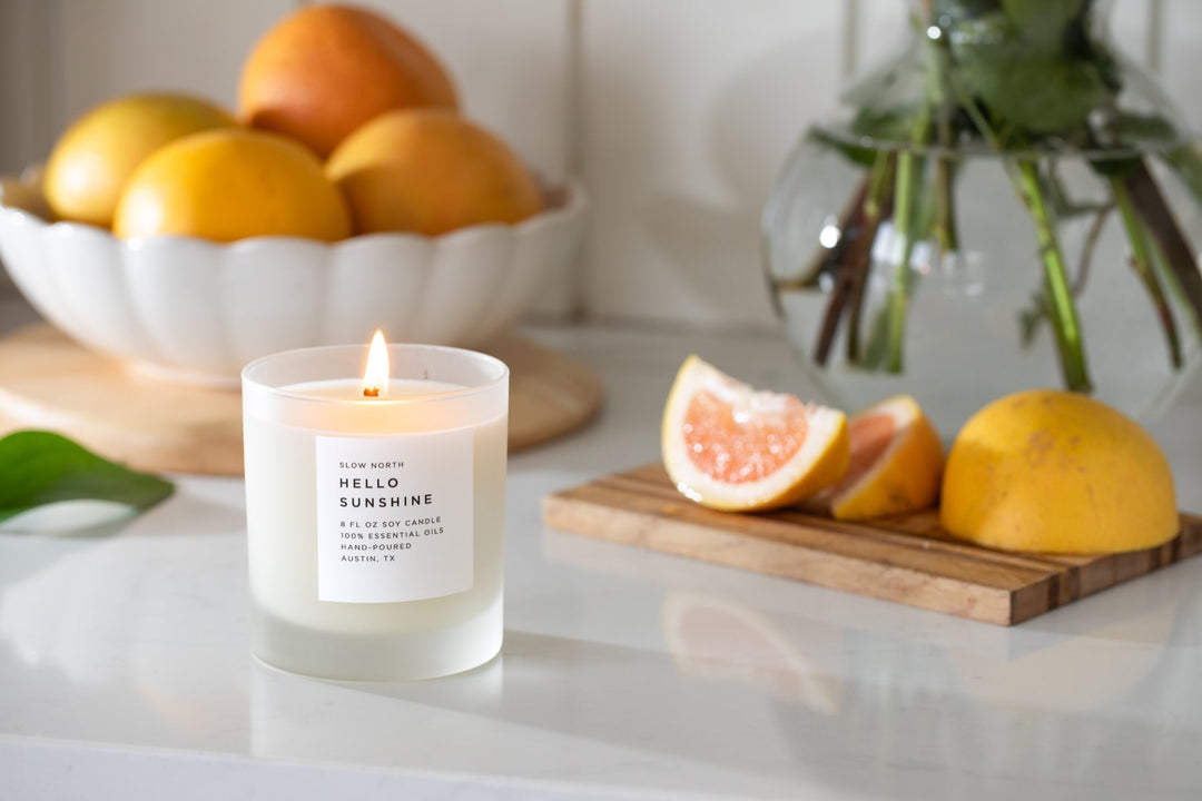 Citrus signature candle with lit wick in a stylish glass jar.