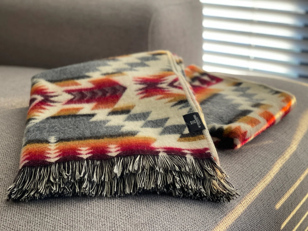 Close-up of black and cream tasseled fringe on a handwoven geometric throw blanket