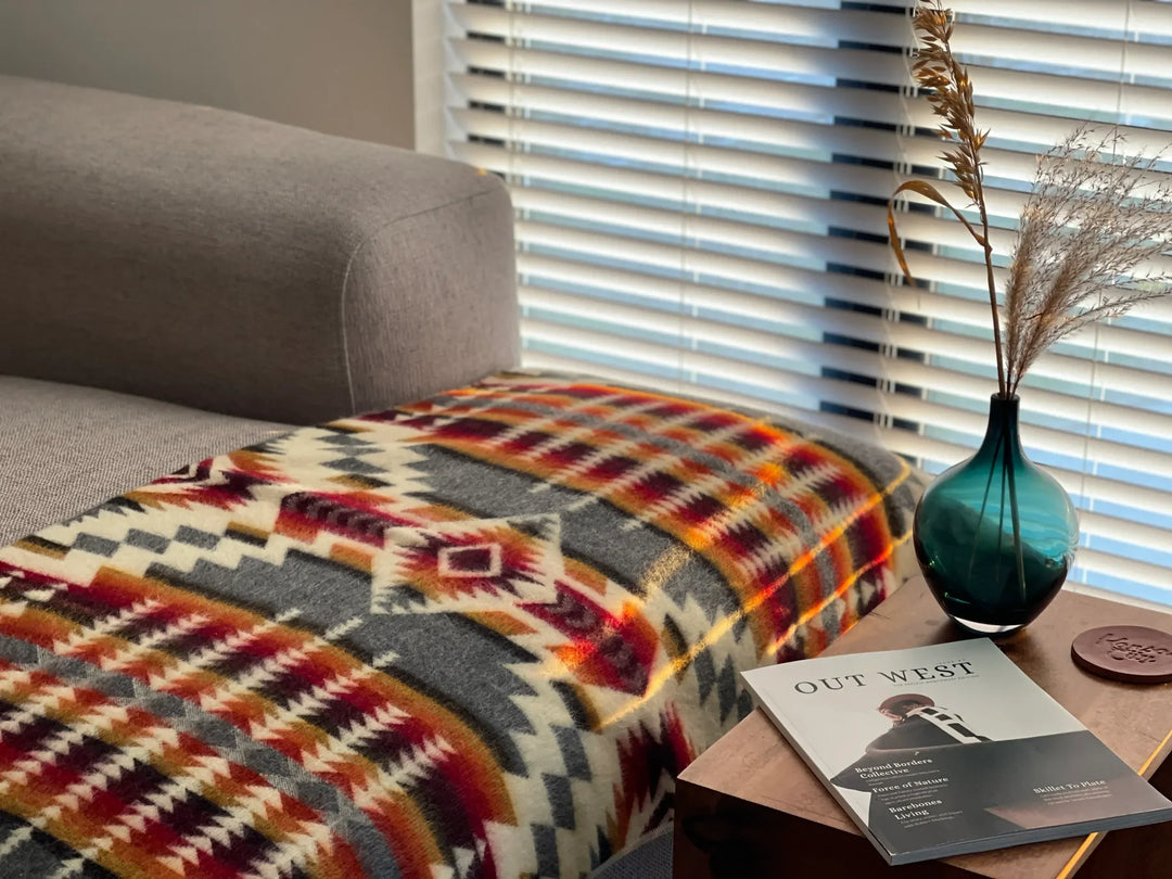 Recycled acrylic throw blanket in a bold Andean pattern layered over a sofa arm