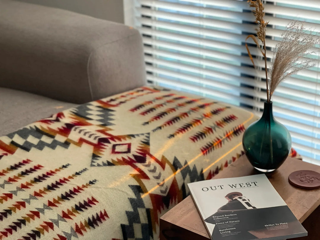 Aztec throw blanket in warm campfire colors on a sofa beside a window and side table