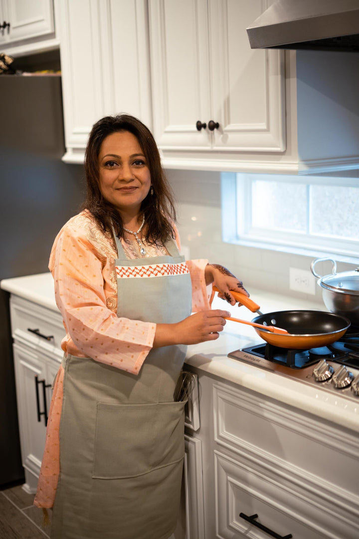 Hand-embroidered sage-green full-length apron with a red-and-white kuffiyeh pattern.