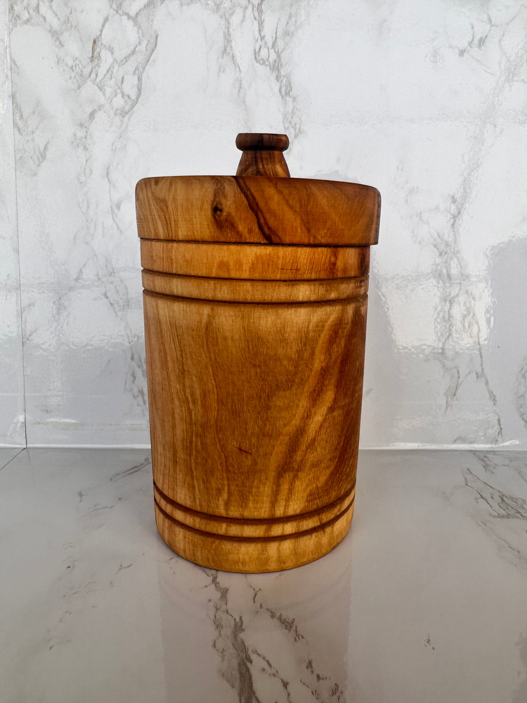 Hand-carved olive wood spice jar with lid, showing detailed wood grain and a secure lid for kitchen storage.