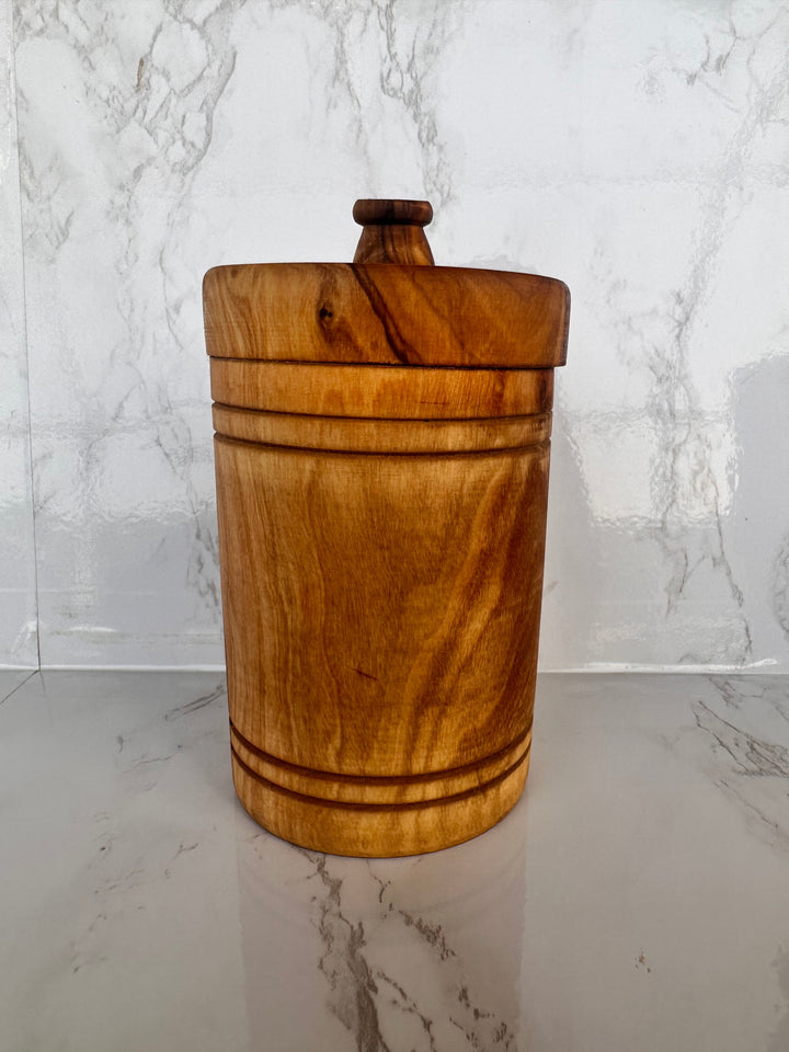 Hand-carved olive wood spice jar with lid, showing detailed wood grain and a secure lid for kitchen storage.