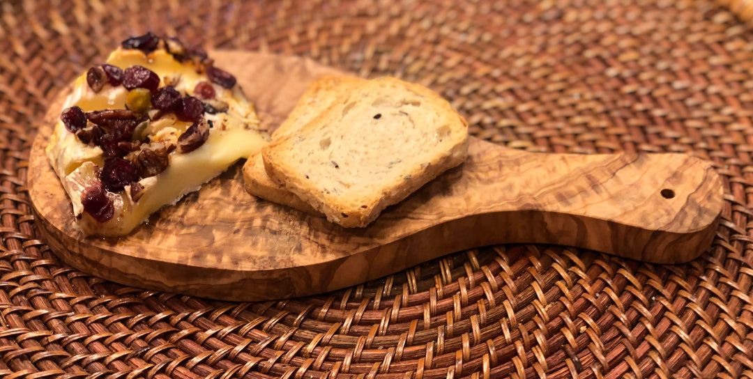 Olive wood cutting board with a Mediterranean handle, showing a smooth, durable surface and natural wood grain.
