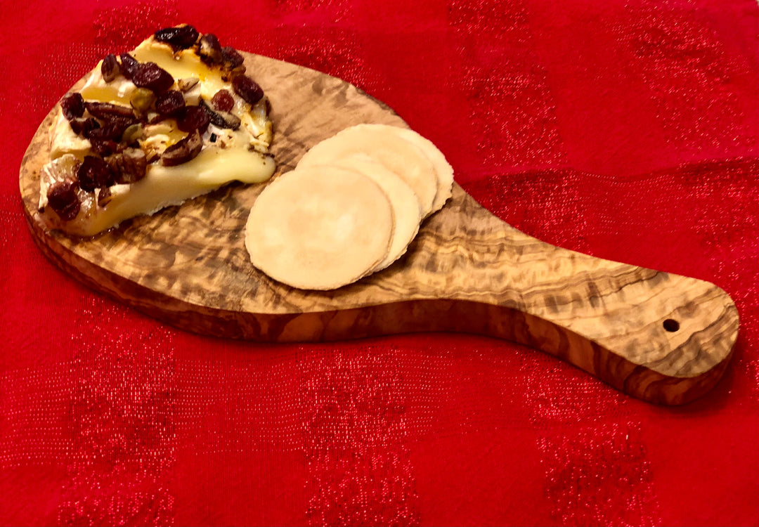 Olive wood cutting board with a Mediterranean handle, showcasing smooth wood grain and a sturdy design for kitchen use.