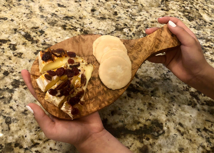 Olive wood cutting board with a Mediterranean handle, natural wood grain, durable surface, and stylish design.