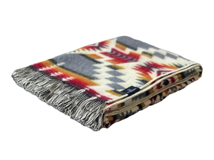 Aztec style fringe throw blanket in cream, grey, red, orange, and mustard, folded with two-tone tasseled fringe