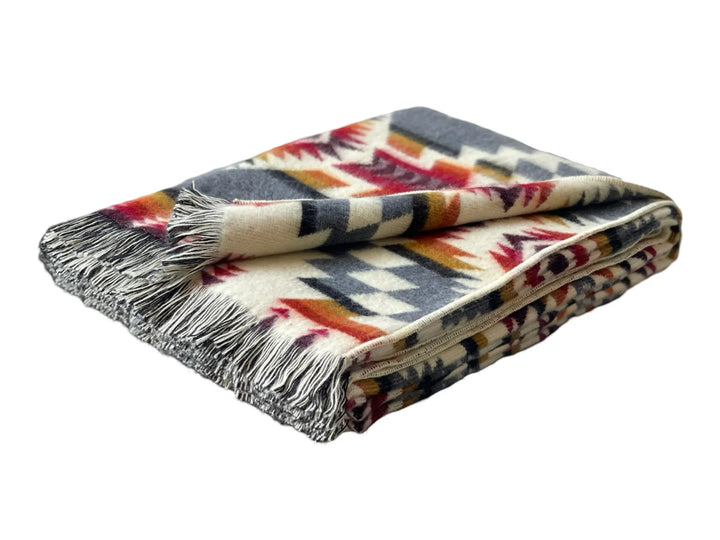 Folded fringe throw blanket with corner turned back to show the two-tone fringe, on white background