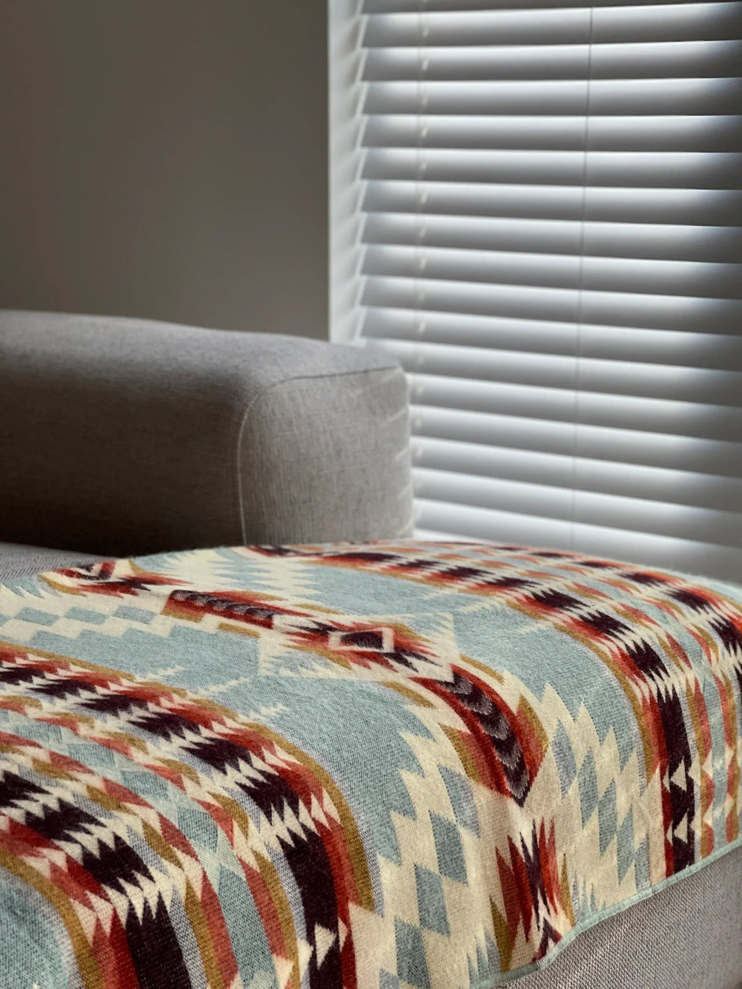 Vibrant Mint fringed throw showing the sage, gold, and maroon geometric weave.