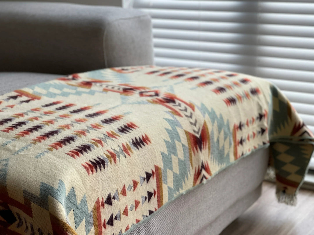 Vibrant Mint Andean throw with tasseled fringe, draped over a sofa.