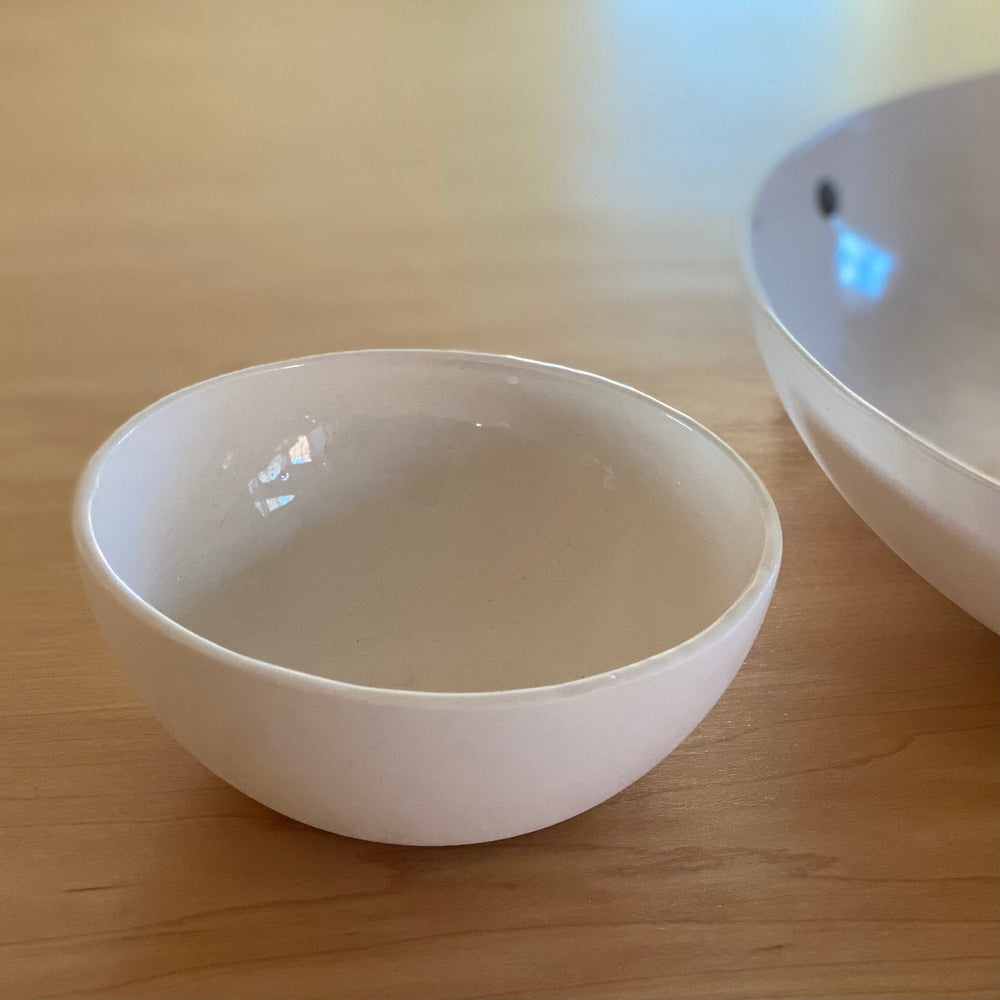 Handmade porcelain bowl in cream with a smooth, rounded shape.
