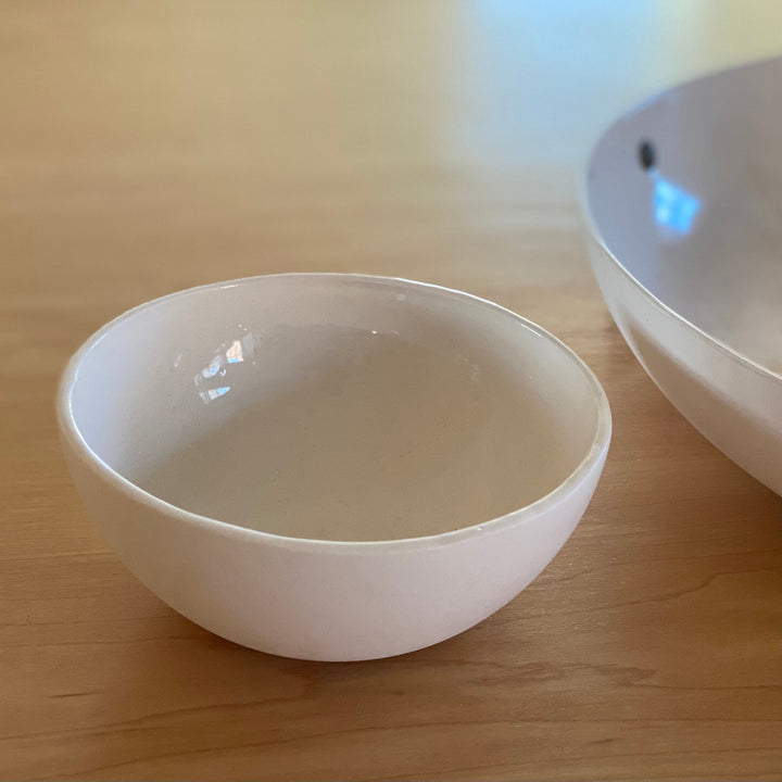 Handmade porcelain bowl in cream with a smooth, rounded shape.