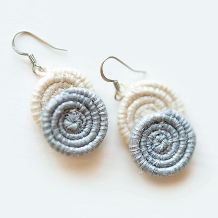 Ice blue woven disc earrings made from sisal fiber on a white background.