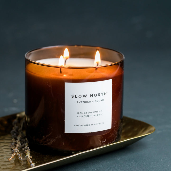 Lavender Cedar three-wick candle in a glass jar for a cozy ambiance.