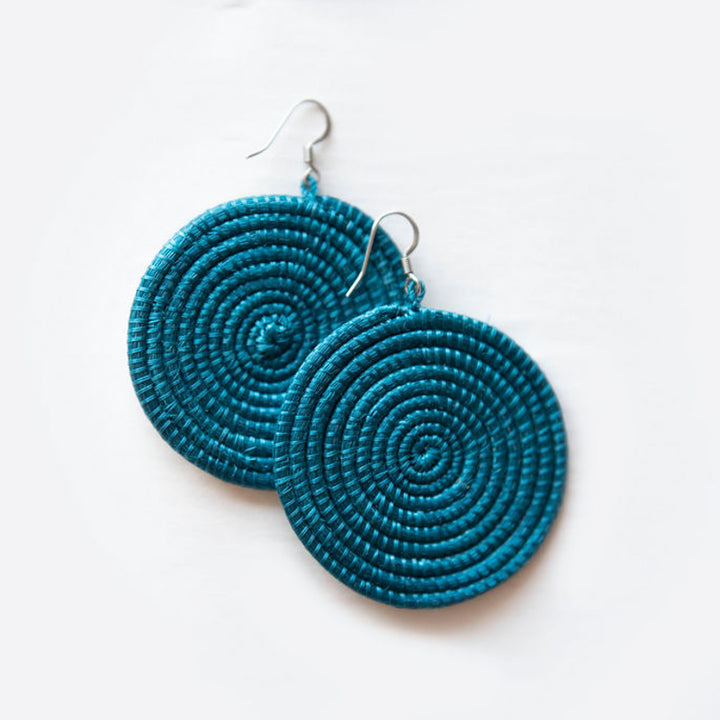 Large woven disc earrings by DC-Azizi Life Inc featuring celestial blue designs on white background.