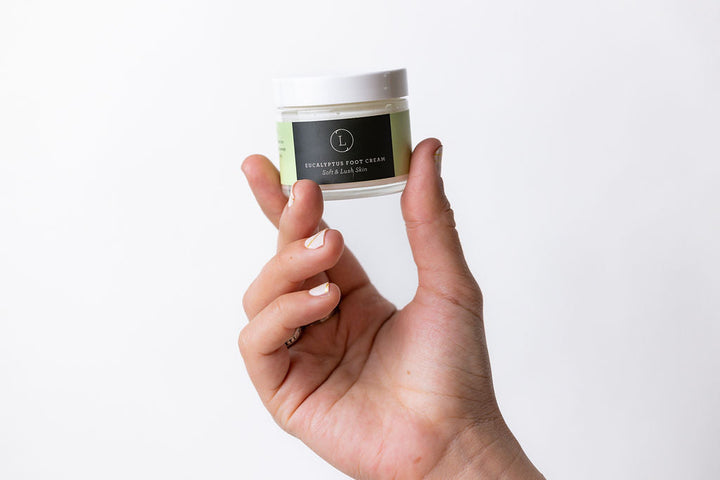 Eucalyptus shea butter foot cream in a jar with eucalyptus leaves and shea butter.