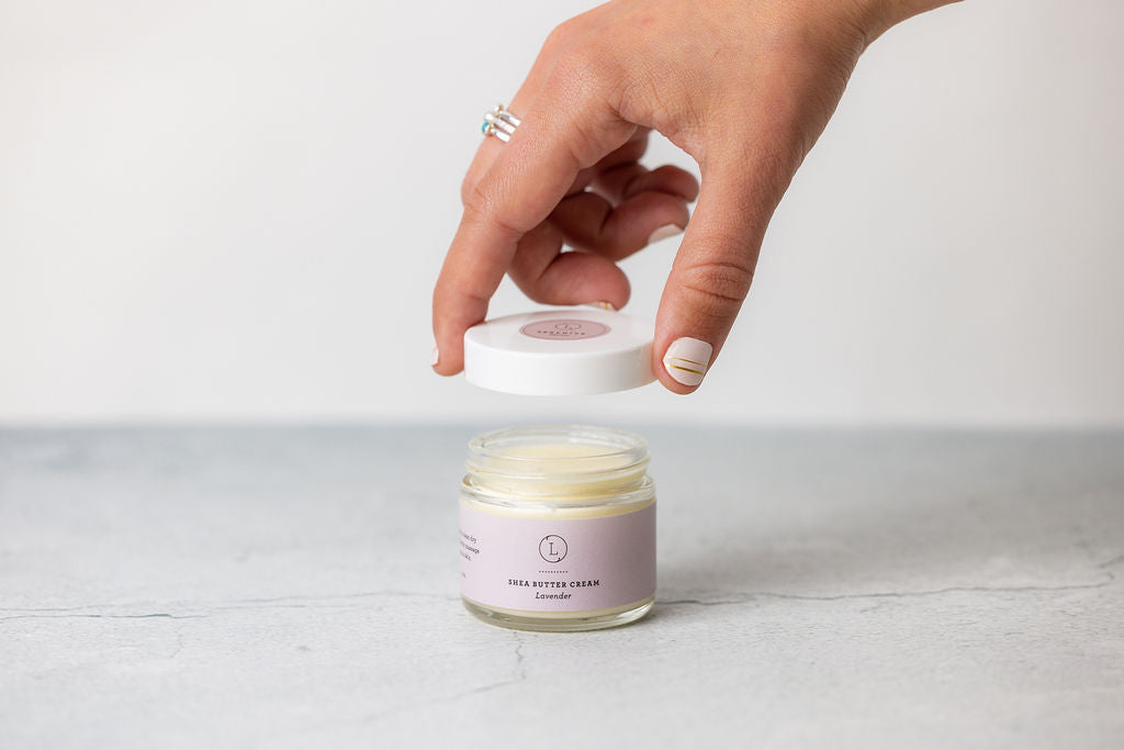 Lavender shea butter body cream in a white jar with a silver lid.