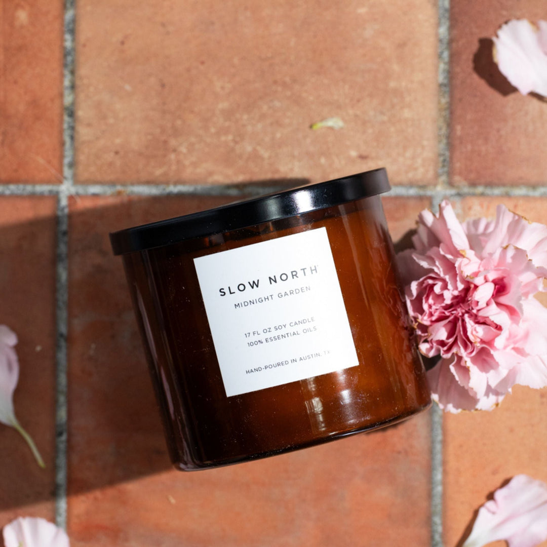 Midnight Garden three-wick candle in a glass jar with floral label, three wicks lit.
