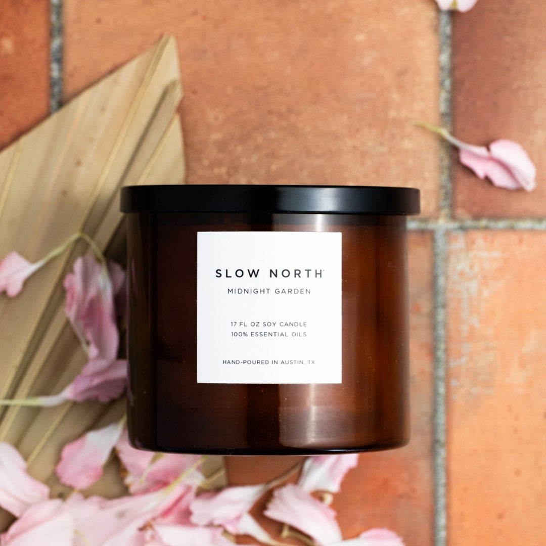 Midnight Garden three-wick candle in a glass jar with floral design.