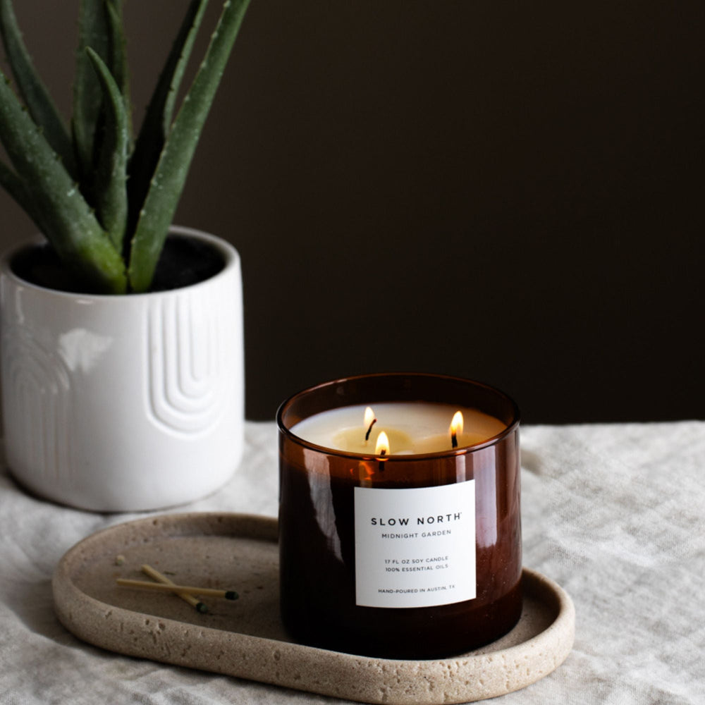 Midnight Garden three-wick candle in a glass jar with floral design.