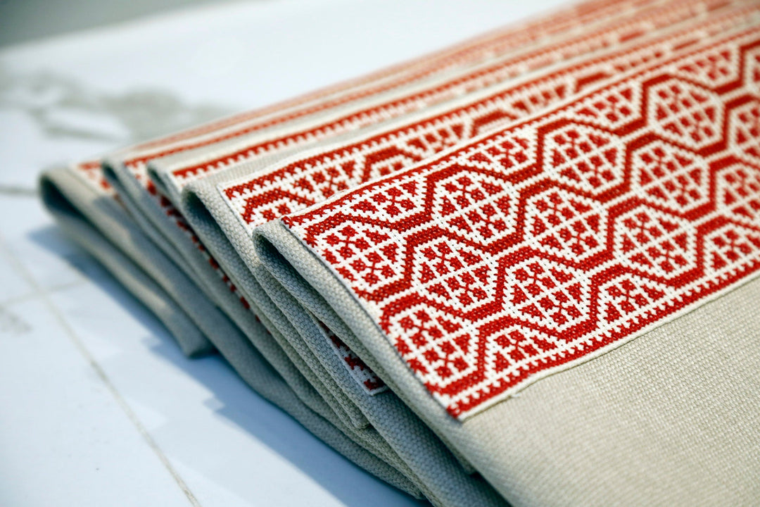 Red tatreez pillow cover displayed on a neutral background.