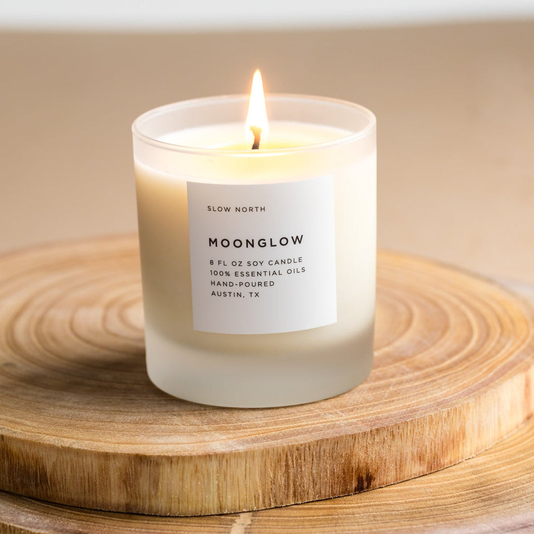 Moonglow signature candle with patchouli and cinnamon notes in a clear glass jar.