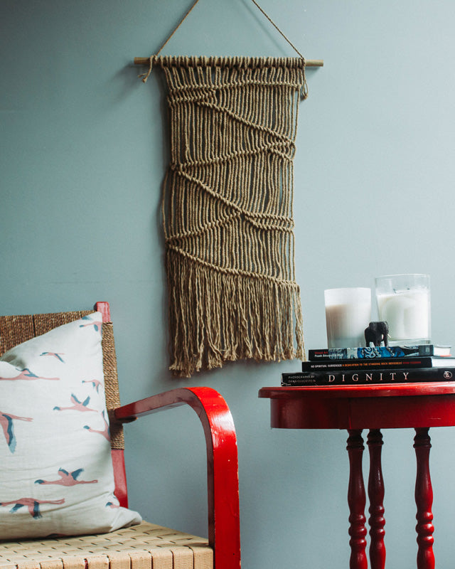 Khaki macrame wall hanging with intricate knotted patterns.