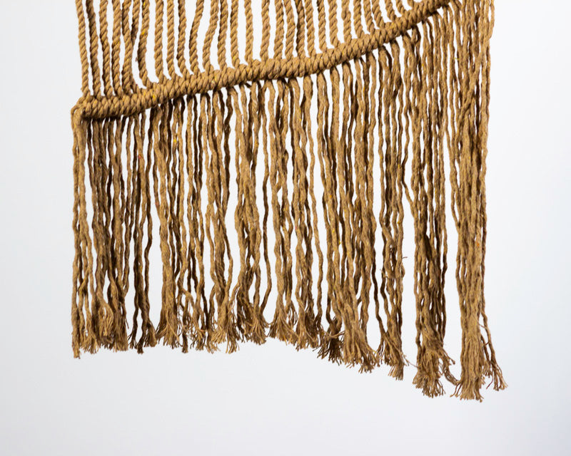 Khaki macrame wall hanging with intricate knots and tassel detail.