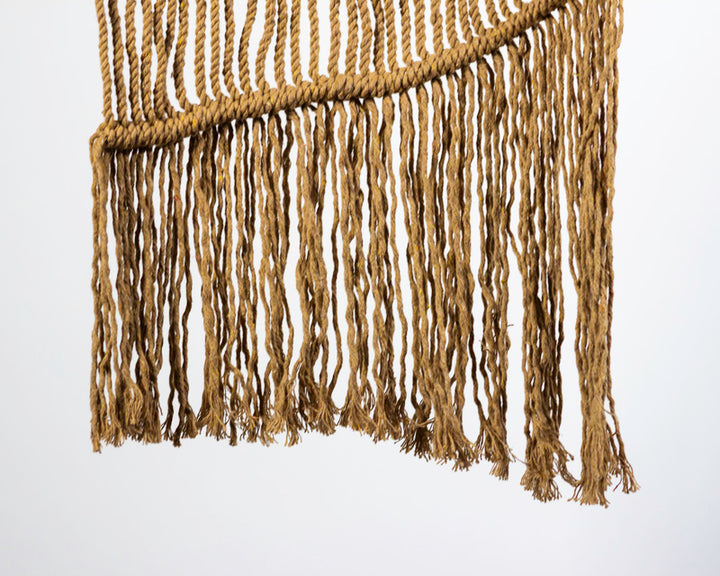 Khaki macrame wall hanging with intricate knots and tassel detail.
