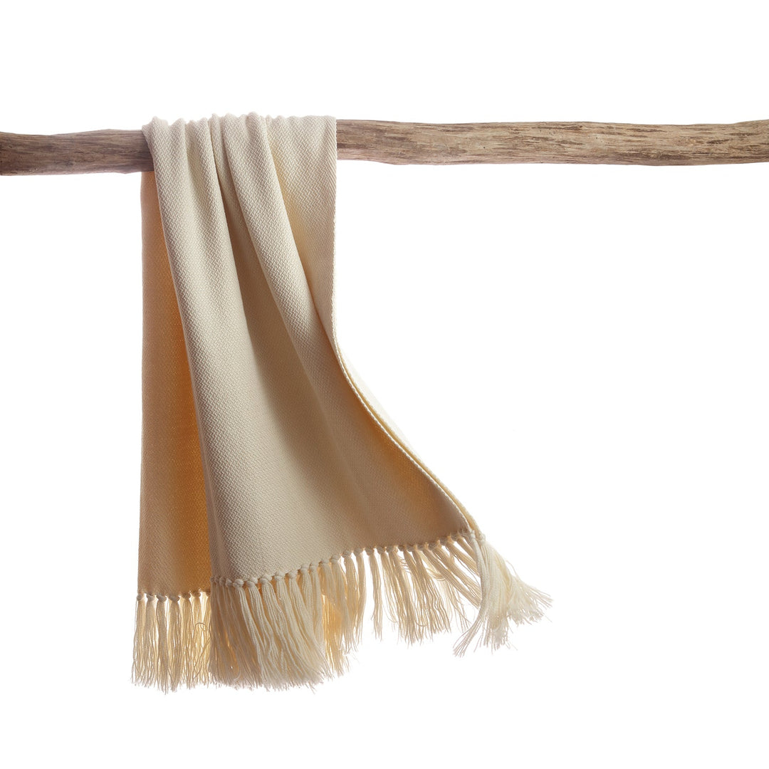 Ivory merino and llama wool throw hanging over a driftwood branch, with hand-knotted fringe.