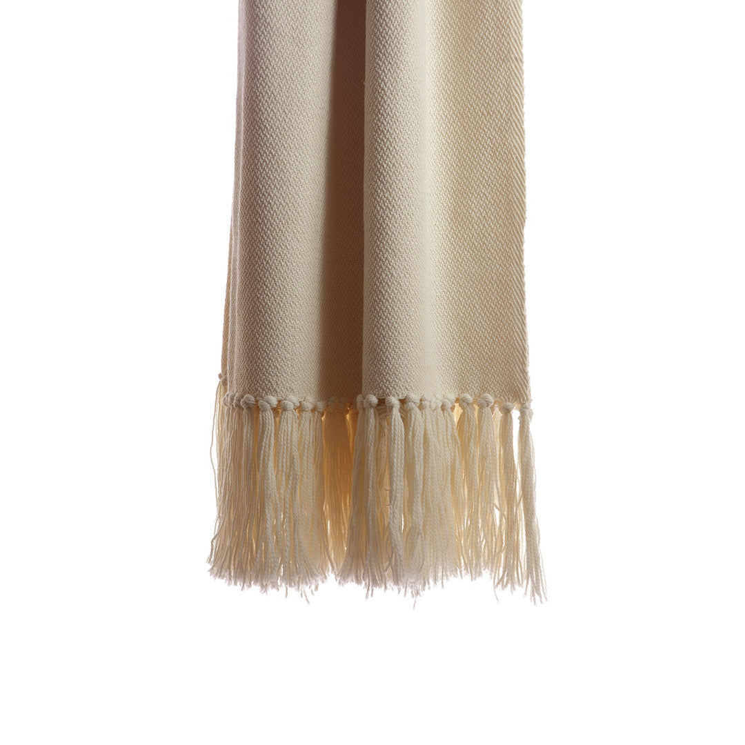 Hand-knotted fringe along the end of an ivory handwoven wool throw.